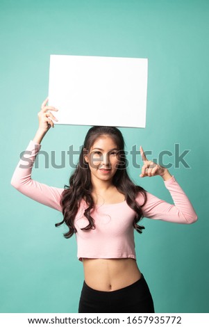 Young Asian woman point to blank sign on cyan background