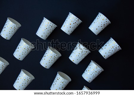 Paper cups with golden dots on a black background. Top view