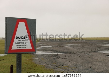 Sign placed at the end of a World War two historic runway which has fallen into disrepair. Focus is on sign. 