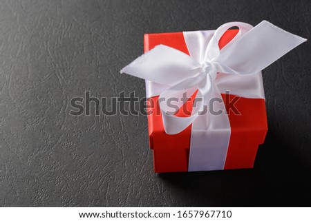 gift red box with white ribbon tied on a bow