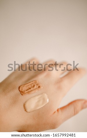 Swatch of tonal foundations of different colors on the girl’s hand