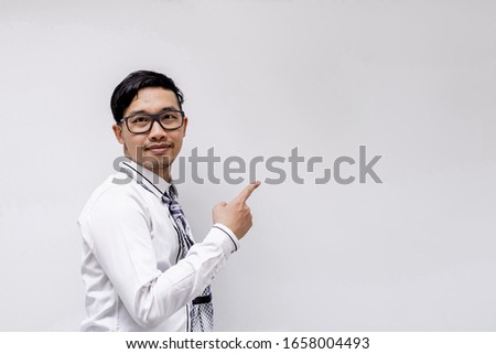 A businessman pointing to the wall.