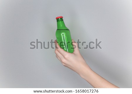 female hand holds a green glass bottle