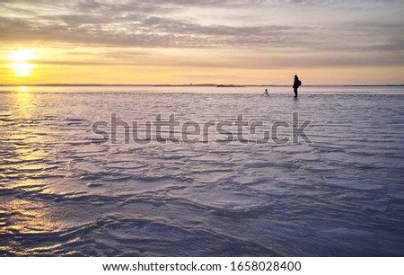 Photographer taking photos on frozen lake in sunset time background