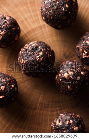 Raw healthy sugar free dessert. Bliss balls made of green buckwheat, nuts and dried fruits on wooden slab close up top view low key Royalty-Free Stock Photo #1658029699
