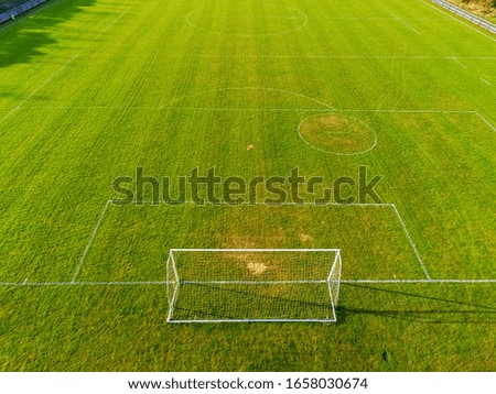 Aerial view on a green football pitch with trees shadows. Nobody. Sunny day.