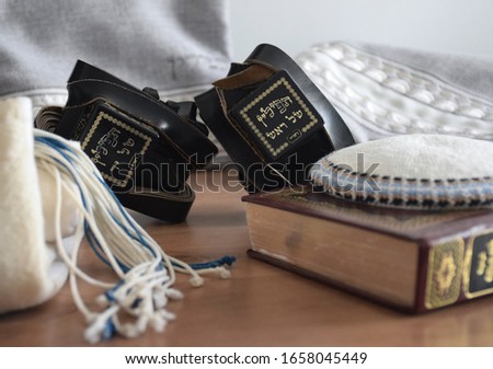 Black Tefillin (Judaica item using for the famous jewish prayer "Shema Israel" - hear us our lord, made from leather), the Jewish bible book and white 'Kippah' (skullcap) and a bag for the Tefillin. Royalty-Free Stock Photo #1658045449