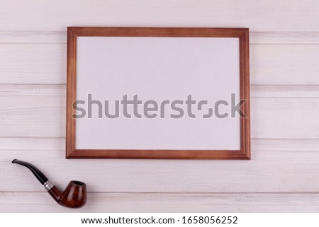 Composition for congratulations. Photo frame and smoking pipe on a white wooden background. View from above. Copy space Father's Day, men.