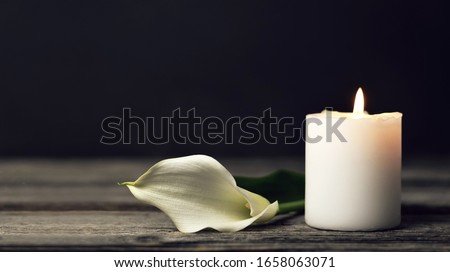 Burning candle and white calla lily on dark background with copy space. Sympathy card   Royalty-Free Stock Photo #1658063071