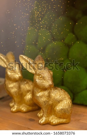 Golden rabbits on wooden background, Easter greeting card concept, toned, with dust texture