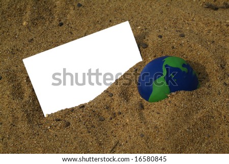 Green and blue globe in the sand