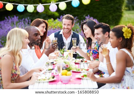 Group Of Friends Enjoying Outdoor Dinner Party Royalty-Free Stock Photo #165808850