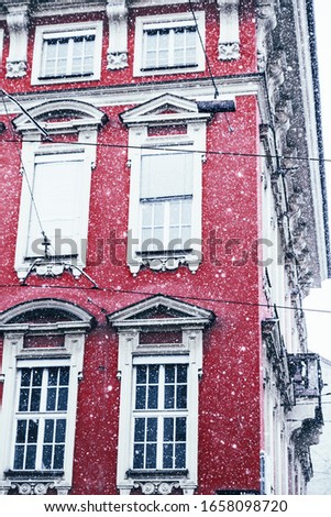 Part of the red building and snowfall on its background
