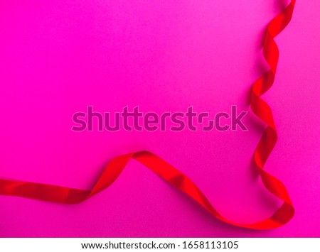 holiday curly red ribbon tape on pink background with copy space