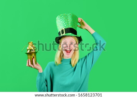 Saint Patrick's Day. Green top hat. Blonde girl in Leprechaun costume holds pot with gold. Leprechaun. Pot with gold. Green leprechaun. Green hat with clover. Traditions of Saint Patrick Day. Royalty-Free Stock Photo #1658123701