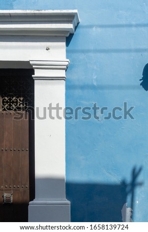 Detail of old, wooden door with cast stone cornices and jamb on a light blue wall. Spanish colonial architectural style in Cartagena, Colombia. High Resolution Photography.