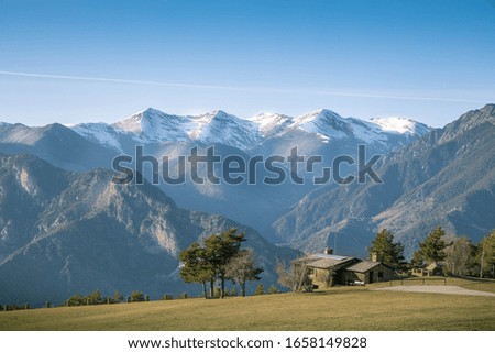 House on a mountain in a cliff with the snowy mountains in the background and the blue sky in Andorra in spring