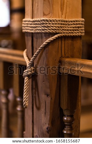 Anchor rope tie up the wooden pillar with copy space. thick rope tied around wooden pillar, close object picture of vintage ship mast background. Wooden pillar top view. Part of the street fence.