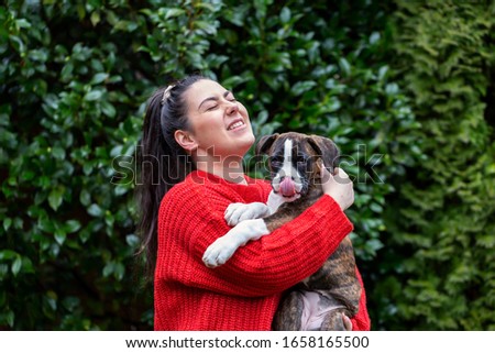 Young White Caucasian Girl with a small cute Boxer Puppy outside in the garden. Taken in Vancouver, British Columbia, Canada.