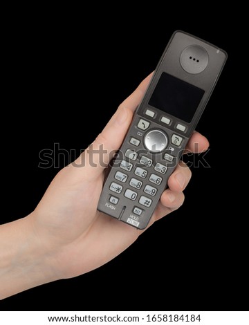 Female hand holds a phone, isolated on black background