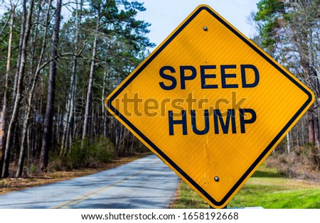 "Speed hump" traffic sign with black letters on a  yellow ,diamond shaped, background.