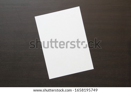 Template of white paper on dark wenge color wooden background. Concept of new idea, business plan and strategy, development and implementation of content. Stock photo with empty space for text.