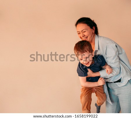 Loving mother playing with her son. Woman holding her kid and they laughing. Mothers day concept. Copy space for banner
