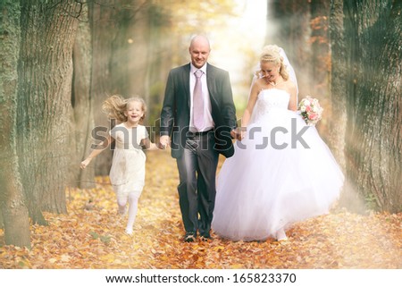 bride, groom and the little girl in the park