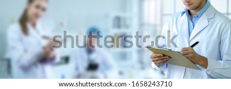 Male Research Scientist write a short note and working in laboratory with team. Medical healthcare technology banner and innovation concept background. Royalty-Free Stock Photo #1658243710