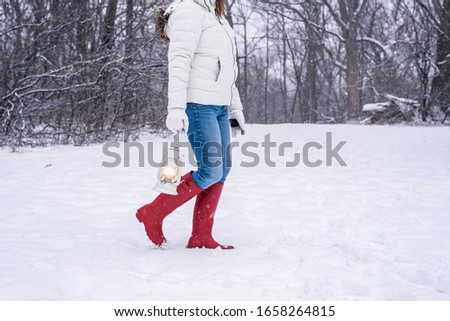 girl holding lantern and walking in the woods in winter