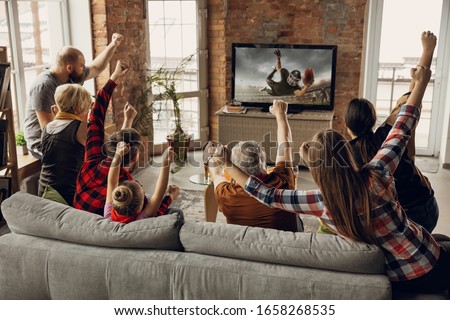 Victory. Excited, happy family watch american football match, championship on the couch at home. Fans emotional cheering for favourite national team. Daughter, dad and grandpa. Sport, TV, having fun. Royalty-Free Stock Photo #1658268535