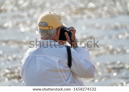 Older man with a camera by the water