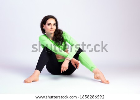 Slim young woman doing yoga practice, doing the splits on a white isolated background. The concept of a healthy lifestyle and a natural balance for women