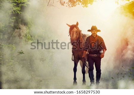 The silhouette of a cowboy man, with a horse on a farm at dusk, sunset