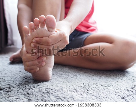 Acute foot pain of thai Asian women, Using hand massage on feet to relieve severe sore feet. Medical health care concept. Royalty-Free Stock Photo #1658308303