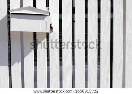 White post box on white wooden fence