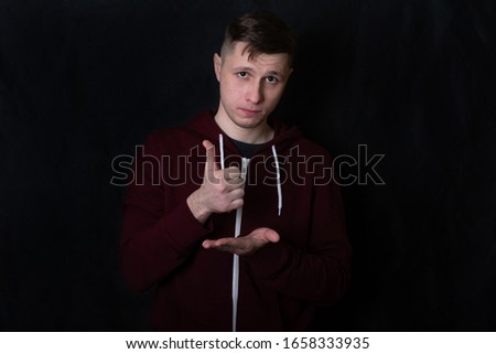 deaf young man shows a gesture to "help". sign language. dark background Royalty-Free Stock Photo #1658333935