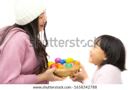 Family with mother and daughter giving a wooden basket group Easter eggs in the spring of easter day, red eggs, blue, purple and yellow on the white background