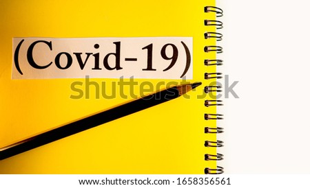 Text "Covit-19" on the yellow book cover and black pencil, have copy space, Concept  Study for ways to prevent and treat epidemics coronavirus or Disease insurance.