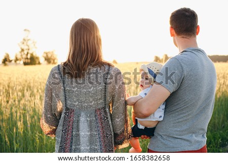 mom, dad and little son in the field at sunset. summer family photo in the village. Dad holds his son on his shoulders. summer sunset and little baby