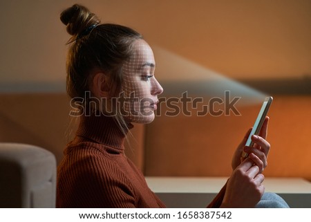 Female scans face using facial recognition system on smartphone for biometric identification. Future digital high tech technology and face id Royalty-Free Stock Photo #1658387542