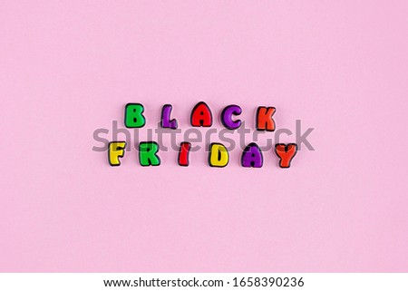 Inscription Black Friday composed of colored letters on a pink background. Discount and advertisement. Seasonal sale in stores. The photo for a banner or poster on the site and on social networks.
