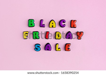 Inscription Black Friday sale composed of colored letters on a pink background. Discount and advertisement. Seasonal sale in stores. The photo for a banner or poster on the site and on social networks