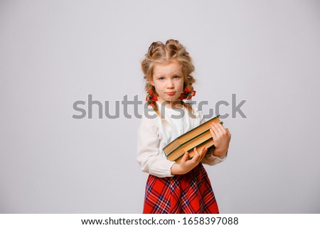 portrait of a child girl in school uniform holding books isolated on a white background