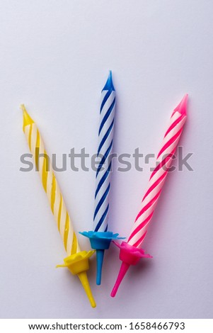 3 birthday candles on white background. For birthday greeting card. Space to insert text. Very colorful, with blue, red, yellow and white. For birthday greeting card.