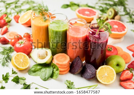freshly squeezed juice, fruit and vegetable smoothies in glass glasses on a white table decorated with a composition of fruit Royalty-Free Stock Photo #1658477587
