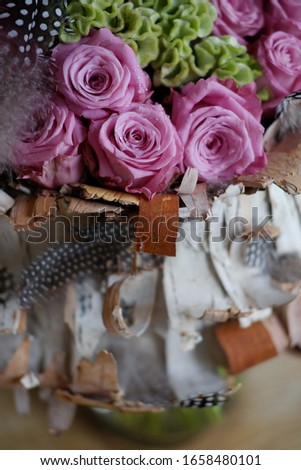 Beautiful spring bouquet close-up with pink roses and green carnations, decorated with feathers and birch bark. Bouquet for the woman you love. Bouquet for International Women's Day and Mother's Day.