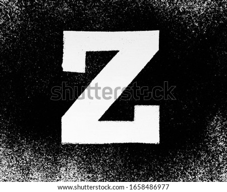 Latin alphabet letters drawn on a black background with powder