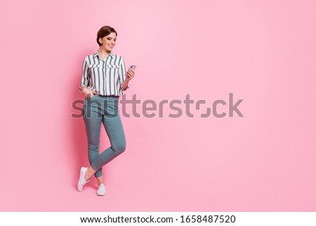 Full length photo of positive cheerful girl have travel summer walk use cell phone read social media news information repost share posts wear modern clothes isolated pink color background