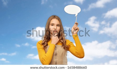communication and people concept - smiling teenage girl holding blank speech bubble over blue sky and clouds background